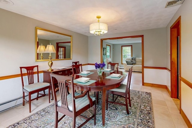 dining room with a chandelier, light tile patterned flooring, and baseboards