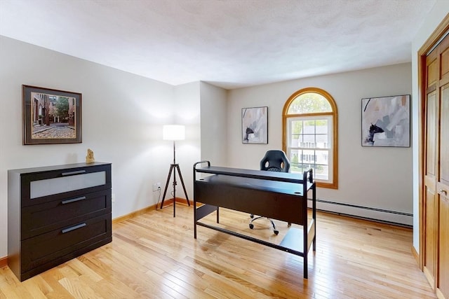 home office with a baseboard radiator, light wood-style flooring, and baseboards