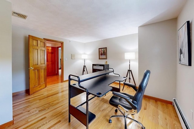bedroom featuring a baseboard radiator, light wood-type flooring, baseboards, and a desk