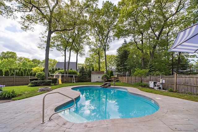 view of pool with a storage shed, an outbuilding, a patio area, and view of scattered trees