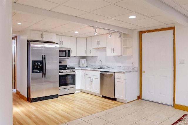 kitchen featuring appliances with stainless steel finishes, a drop ceiling, light countertops, baseboards, and white cabinets