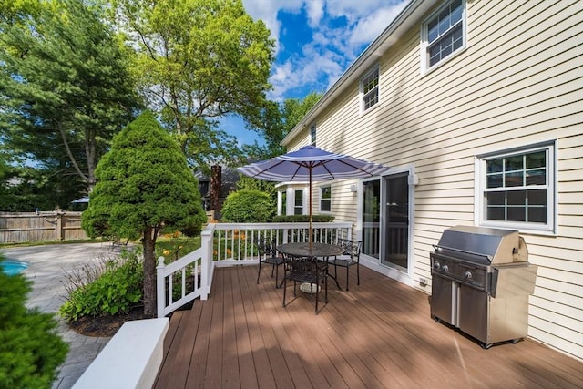 wooden deck featuring outdoor dining space, grilling area, and fence