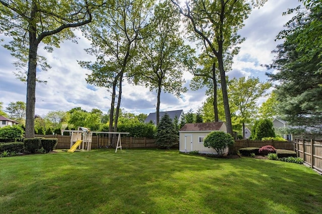 view of yard featuring a storage shed, a playground, and an outbuilding