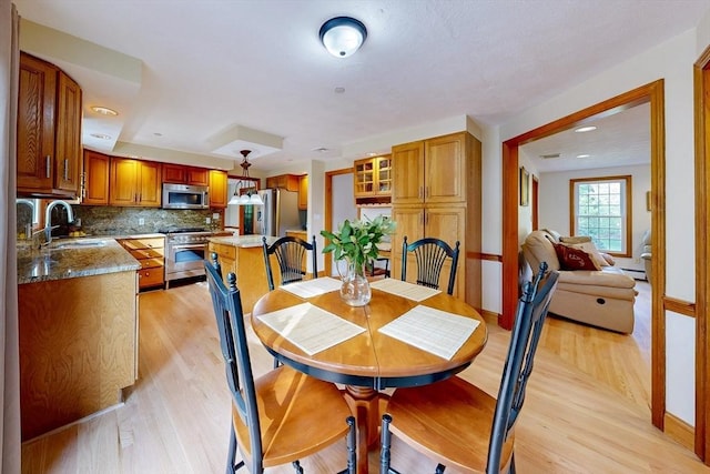 dining room with light wood-type flooring, baseboards, baseboard heating, and recessed lighting