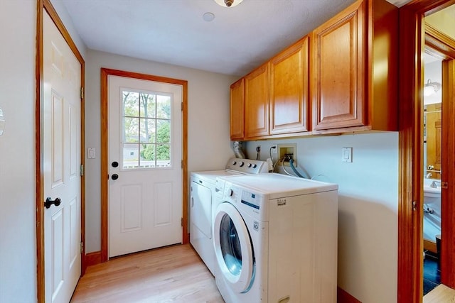 washroom with cabinet space, light wood-style flooring, and separate washer and dryer
