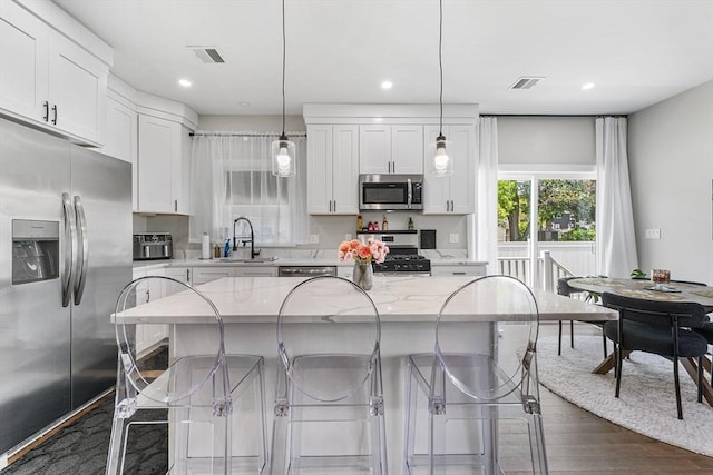 105 Depot St Unit A, Milford, MA 01757 - kitchen with appliances with stainless steel finishes, a sink, white cabinetry, light stone countertops, and a breakfast bar