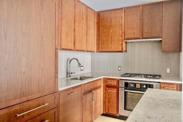 kitchen with backsplash, light stone countertops, sink, and appliances with stainless steel finishes