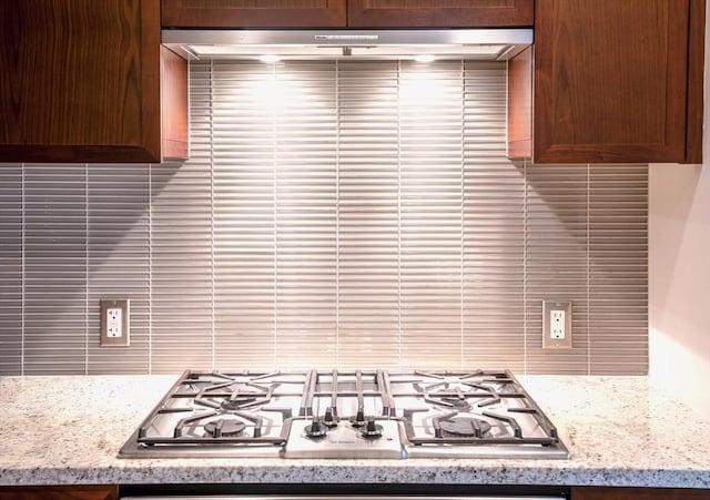 kitchen with backsplash, light stone countertops, and stainless steel gas stovetop