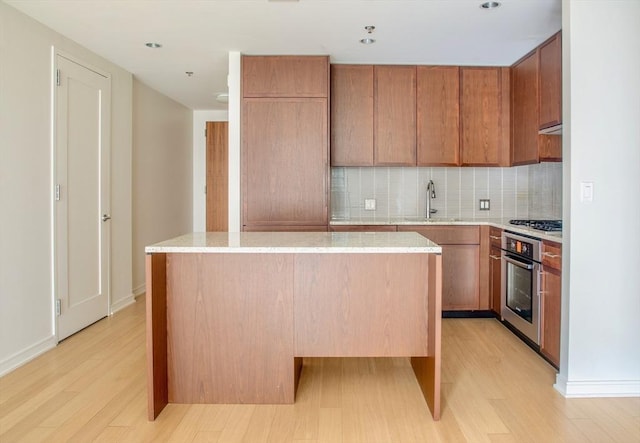 kitchen featuring sink, a center island, tasteful backsplash, light hardwood / wood-style flooring, and appliances with stainless steel finishes