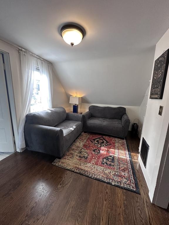 living room featuring lofted ceiling and dark hardwood / wood-style floors