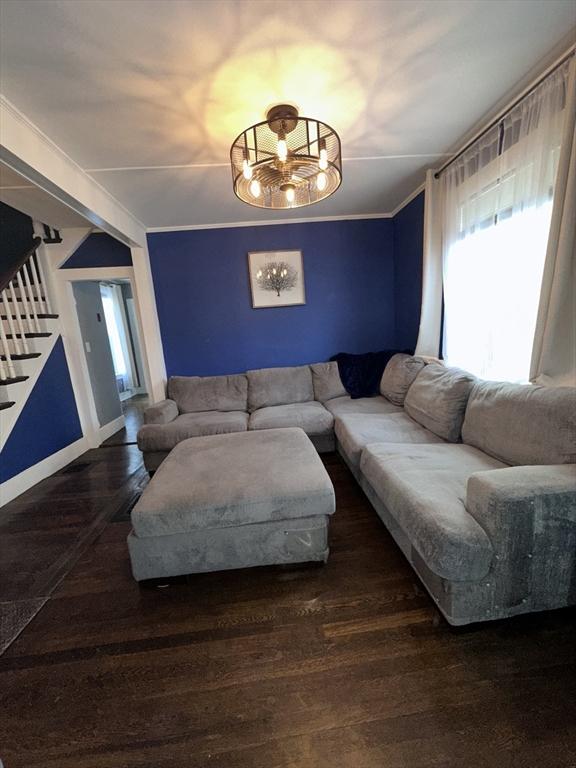 living room with crown molding, dark hardwood / wood-style floors, and a notable chandelier