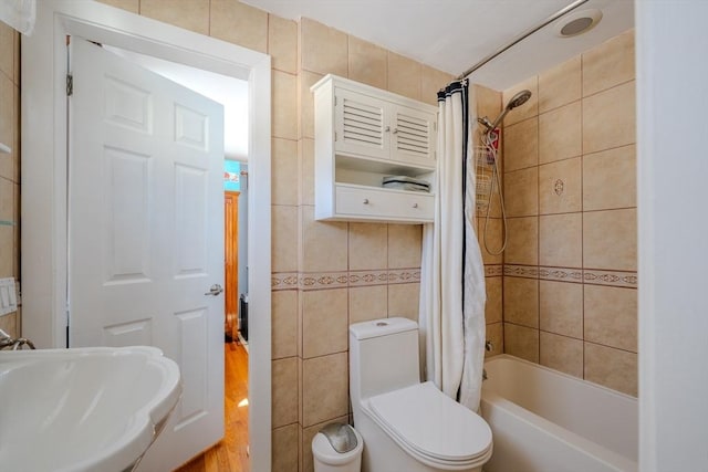 full bathroom with shower / bath combo, sink, tile walls, and toilet