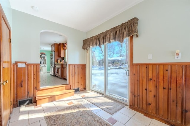 entryway with wood walls and light tile patterned floors