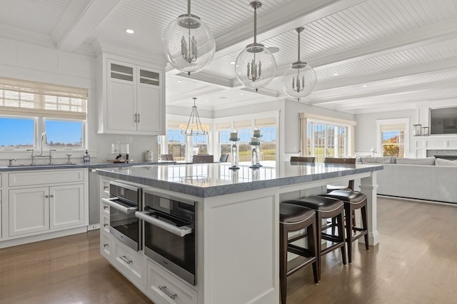 kitchen with a kitchen island, white cabinetry, sink, and hanging light fixtures