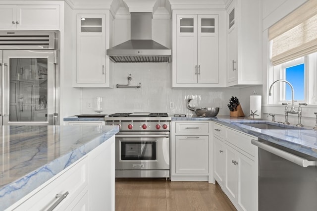 kitchen featuring white cabinets, sink, stainless steel appliances, and wall chimney range hood