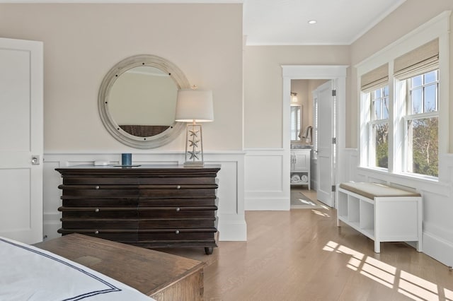 bedroom with connected bathroom, crown molding, and light hardwood / wood-style floors