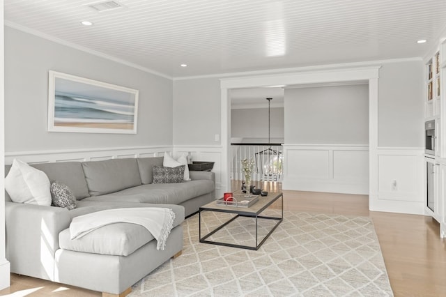 living room featuring a chandelier, hardwood / wood-style flooring, and crown molding