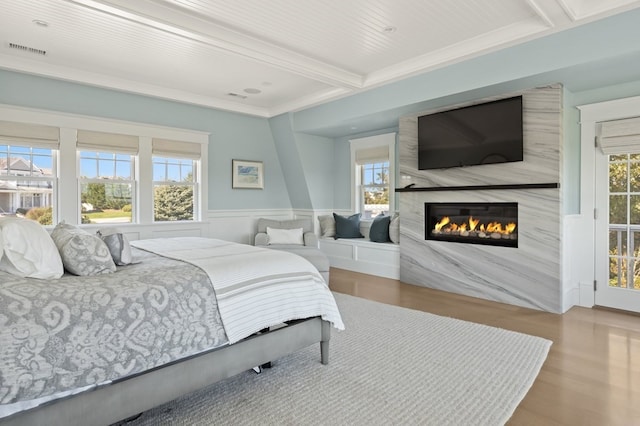 bedroom with beam ceiling, a large fireplace, hardwood / wood-style flooring, and multiple windows