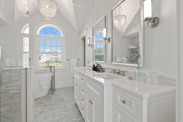 bathroom with a tub, vanity, lofted ceiling, and an inviting chandelier