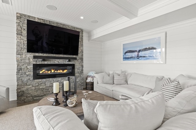 living room featuring hardwood / wood-style flooring, beam ceiling, a stone fireplace, and wooden ceiling