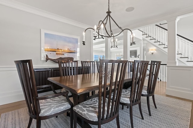 dining area featuring a chandelier, hardwood / wood-style flooring, decorative columns, and crown molding