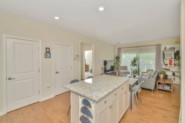 110 Trotter Rd Unit 104, Weymouth, MA 02190 - kitchen featuring open floor plan, light wood-type flooring, a center island, and white cabinets