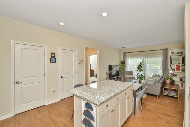 110 Trotter Rd Unit 104, Weymouth, MA 02190 - kitchen featuring open floor plan, light wood finished floors, a kitchen island, white cabinetry, and recessed lighting