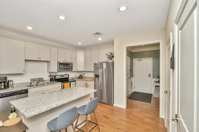110 Trotter Rd Unit 104, Weymouth, MA 02190 - kitchen with appliances with stainless steel finishes, a breakfast bar, light wood finished floors, a kitchen island, and recessed lighting