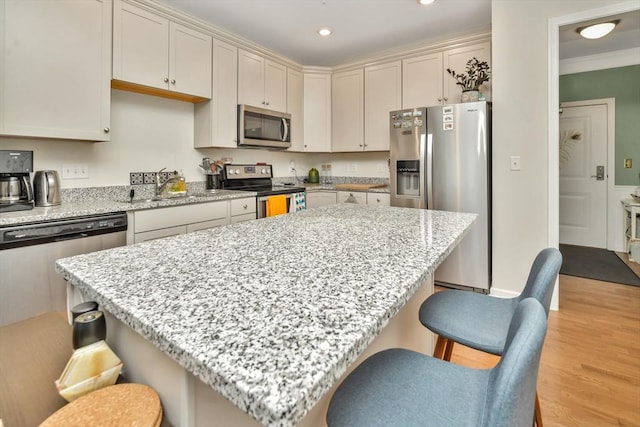 110 Trotter Rd Unit 104, Weymouth, MA 02190 - kitchen with stainless steel appliances, a kitchen bar, light wood-style floors, recessed lighting, and light stone counters