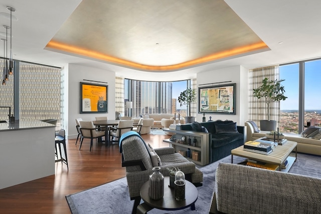 living room with dark hardwood / wood-style flooring, floor to ceiling windows, and a tray ceiling