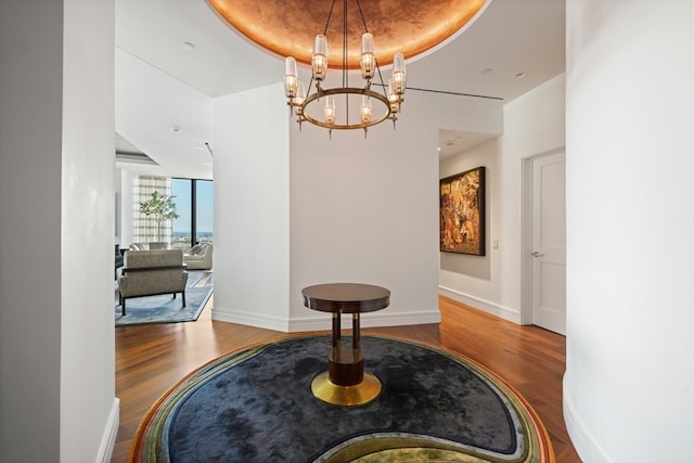 hall featuring a raised ceiling, an inviting chandelier, and hardwood / wood-style floors