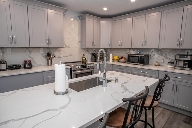 32 Leverett Rd, Shutesbury, MA 01072 - kitchen with gray cabinetry, appliances with stainless steel finishes, tasteful backsplash, a breakfast bar, and recessed lighting