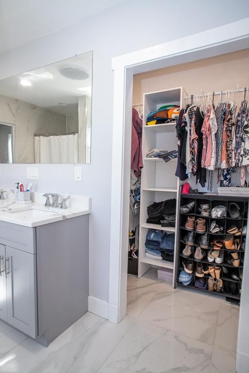 32 Leverett Rd, Shutesbury, MA 01072 - bathroom with marble look tiles, vanity, a spacious closet, and baseboards