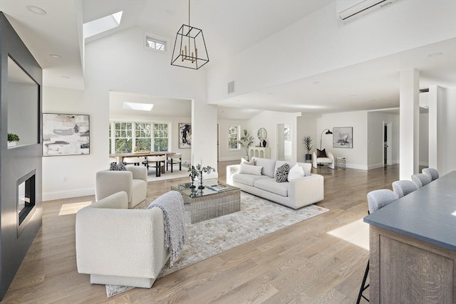 living area with wood finished floors, visible vents, baseboards, a skylight, and a towering ceiling