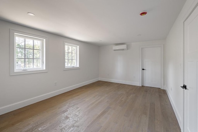 empty room with an AC wall unit, wood finished floors, and baseboards