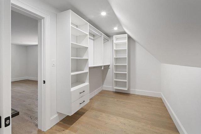walk in closet with vaulted ceiling and light wood finished floors