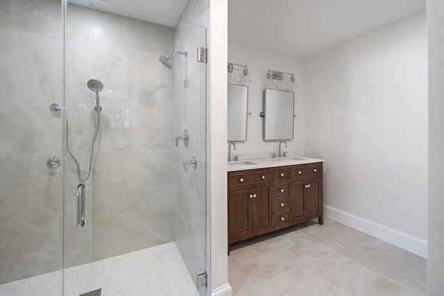 full bath featuring a shower stall, double vanity, baseboards, and a sink