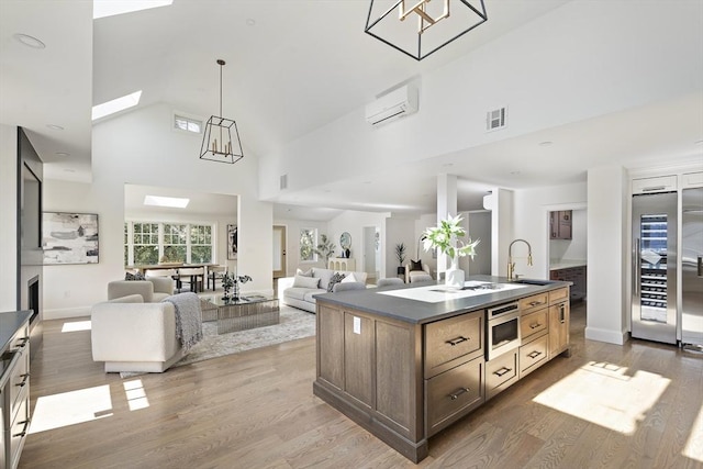 kitchen featuring dark countertops, visible vents, stainless steel microwave, a wall mounted AC, and a sink