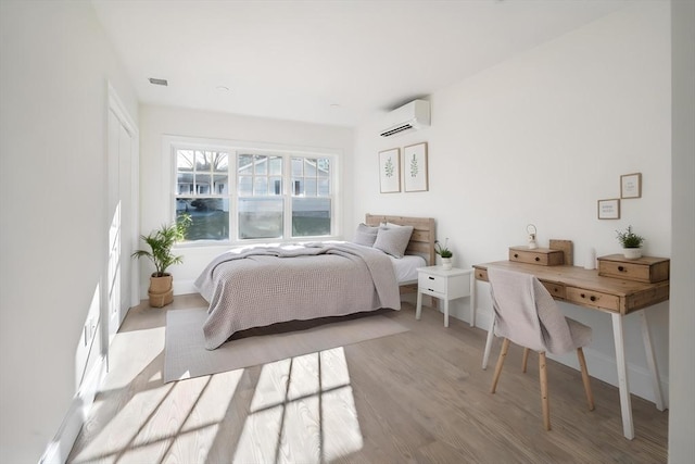 bedroom with wood finished floors, visible vents, and a wall mounted AC