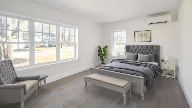 bedroom with wood finished floors, baseboards, and a wall mounted AC