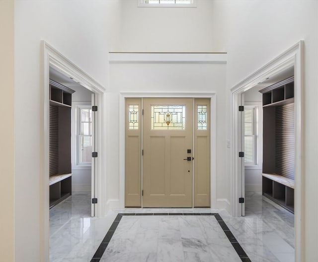 entryway featuring baseboards, a high ceiling, and marble finish floor