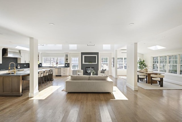 living room featuring baseboards, lofted ceiling with skylight, and wood finished floors
