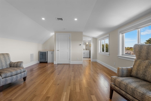 sitting room featuring washer / dryer, lofted ceiling, light wood-type flooring, and beverage cooler