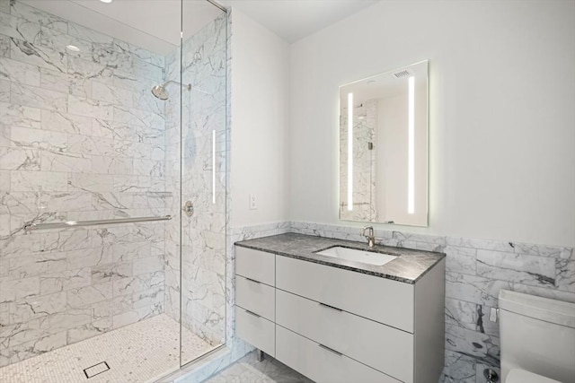 bathroom featuring vanity, tile walls, toilet, and a tile shower