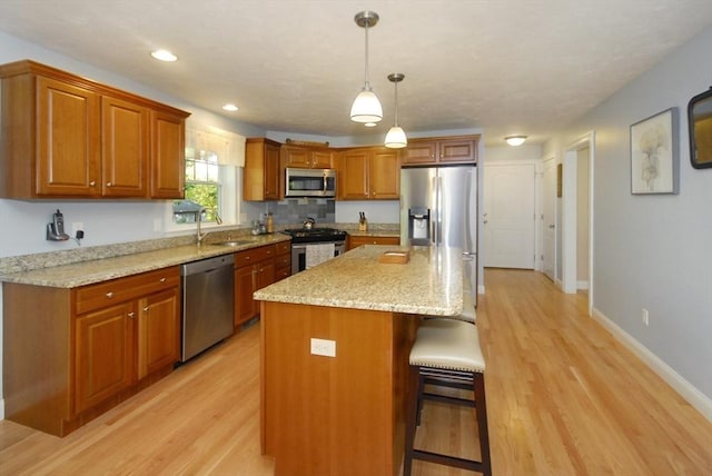 9 Pine Grove Rd, Westford, MA 01886 - kitchen featuring a kitchen breakfast bar, brown cabinets, a sink, light wood finished floors, and stainless steel appliances
