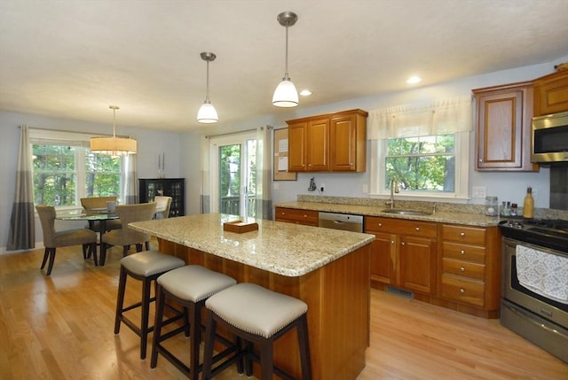 9 Pine Grove Rd, Westford, MA 01886 - kitchen with brown cabinets, light stone counters, a sink, light wood-style flooring, and stainless steel appliances