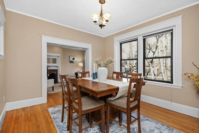 dining space with crown molding, a chandelier, and light wood-type flooring