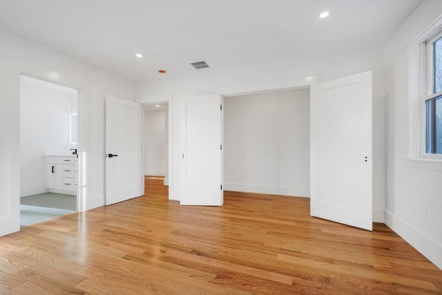 unfurnished bedroom with light hardwood / wood-style floors and ensuite bath