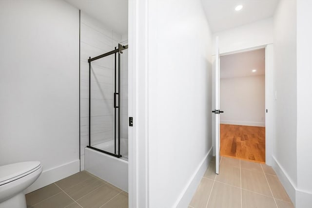 bathroom with tile patterned floors, toilet, and bath / shower combo with glass door