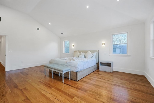 bedroom featuring light wood-type flooring, high vaulted ceiling, and multiple windows